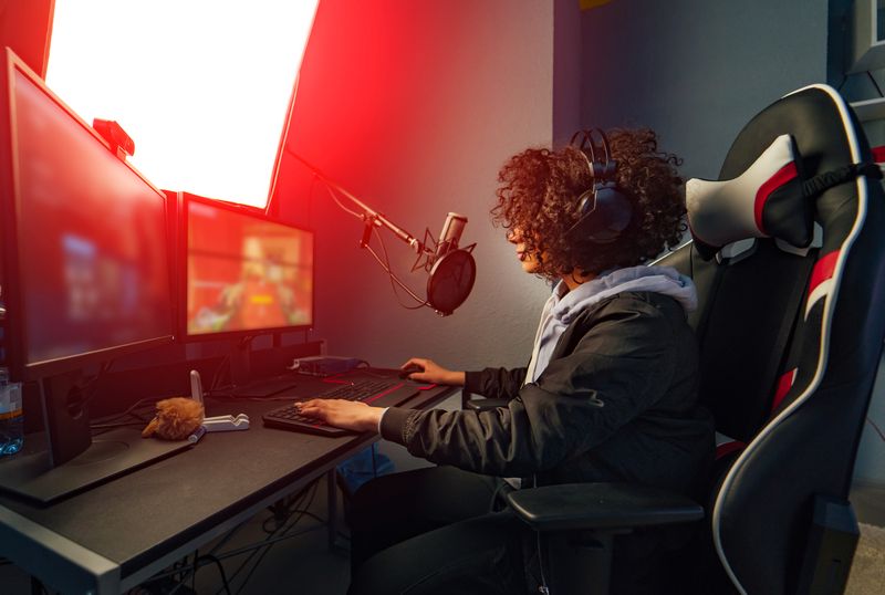 Professional Girl Gamer Plays In Video Game On Her Computer. She's Participating In Online Cyber Games Tournament, Plays At Home, Or In Internet Cafe. She Wears Gaming Headset
